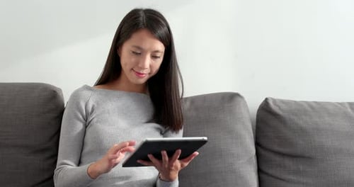 Woman Uses Tablet Device on Couch Indoors