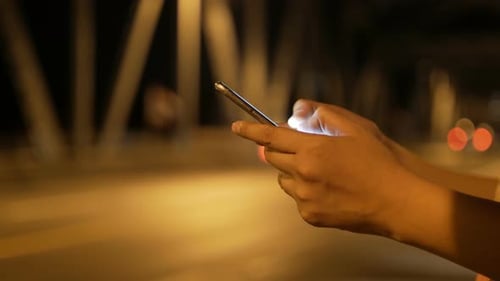 Hands Using a Cell Phone at Night