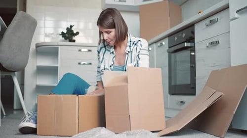 Female Packs Dishes in Kitchen