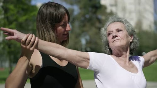 Woman Assists Senior Woman With Arm Stretches