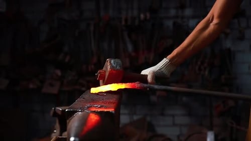 Slow Motion Close Up Hand with the Hammer of Blacksmith Man Forges a Metal Product in Dark Indoors