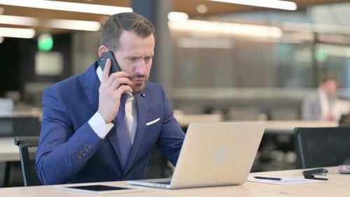 Businessman Talking on Phone at Modern Desk