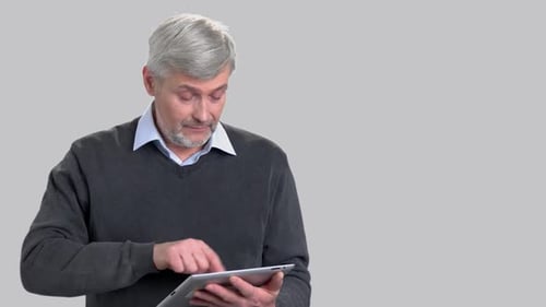 Man Uses Tablet Device Against Gray Backdrop