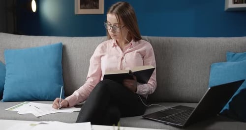 Woman Studying at Home with Book and Laptop
