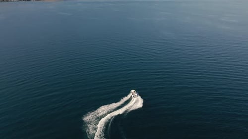 Drone View Of Speedboat Making Quick Turns On Vibrant Blue Water