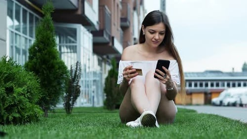 Young Woman Using Credit Card and Smartphone Outdoors