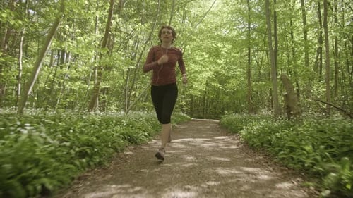Woman Taking a Run By the Forest Path Towards the Camera