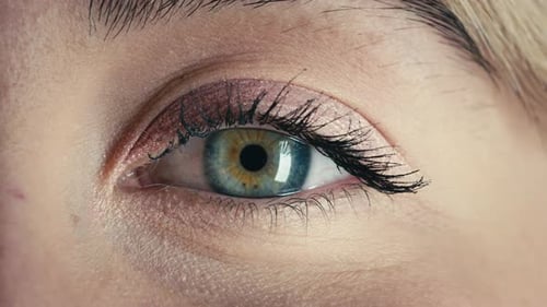 Ojo azul de una hermosa chica modelo que se abre lentamente