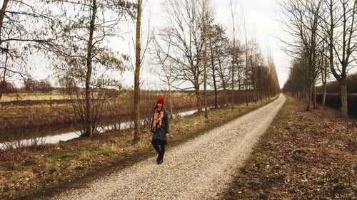 Woman Walking on Gravel Path in Rural Setting