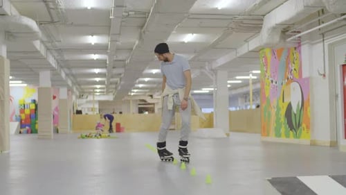 Man Practicing Inline Skating Around Cones Indoors