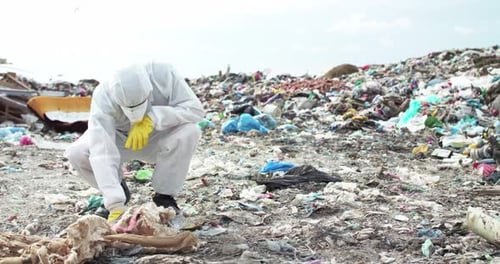 Person Examining Trash at Landfill in Protective Suit
