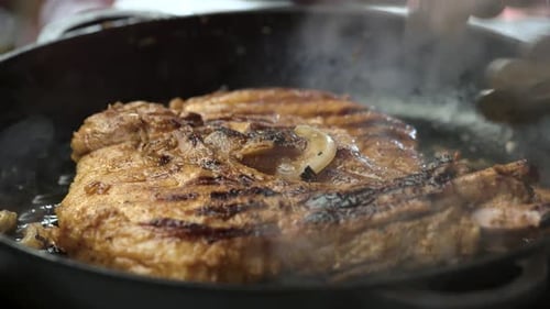 Juicy Steak Cooking in a Cast Iron Pan