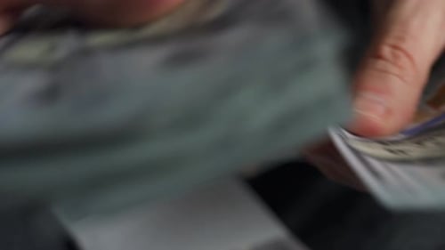 Manos contando billetes en dólares estadounidenses o pagando en efectivo