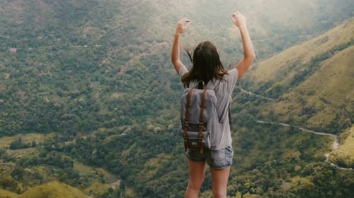 Back View Happy Young Tourist Woman with Backpack and Arms Wide Open, Touching Hair Watching Epic