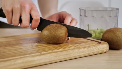 Cutting a Kiwi Fruit on Cutting Board