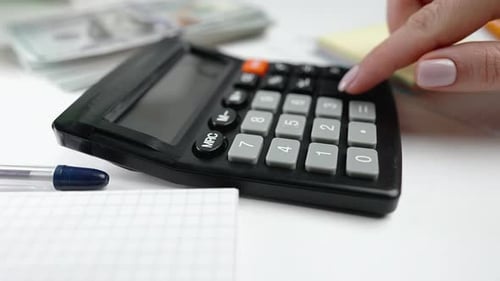 Experta financiera presionando botones en la calculadora para analizar los cargos de la