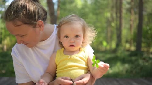 Little Cute Baby Toddler Girl Blonde with Curls on Mother's Arms