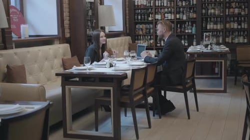 Pretty Brunette Woman and Blond Bearded Man Sitting at the Table in the Cafe Working