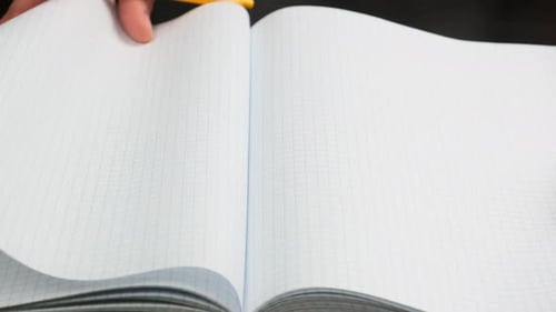 woman's hand turns over blank white sheets of a school notebook into a cage