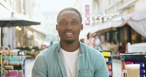Man Smiling at Cafe in Urban Setting