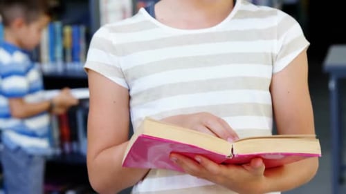 Schoolgirl reading book in library