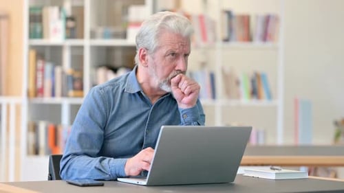Man Coughing While Working on Laptop at Desk
