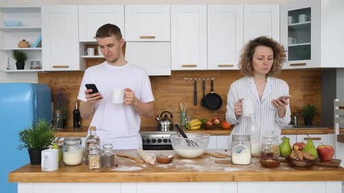 Couple in Kitchen Using Smartphones With Coffee