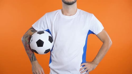 Adult Holds and Points to Soccer Ball