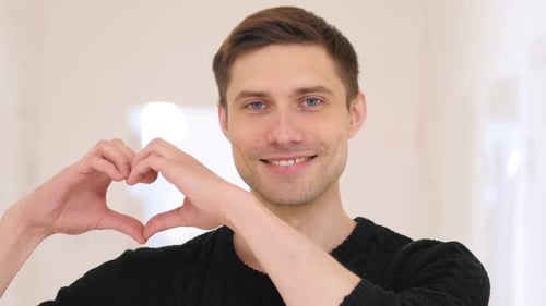 Young Adult Makes Heart Symbol With Hands