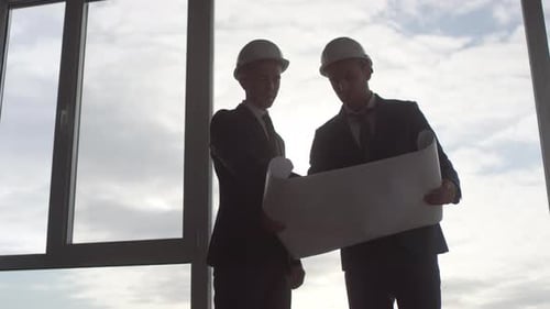 Bauleiter studieren Blueprint vor Panoramafenster