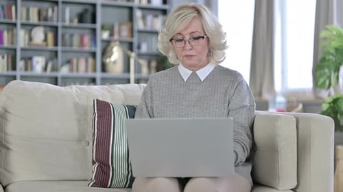 Senior Woman Using Laptop at Home Coughs