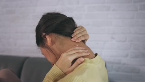 Woman Massaging Neck and Shoulders Indoors