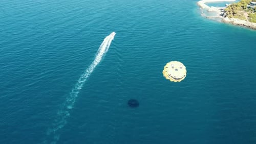 Parasailing behind a boat couple flies over the sea on a parachute.