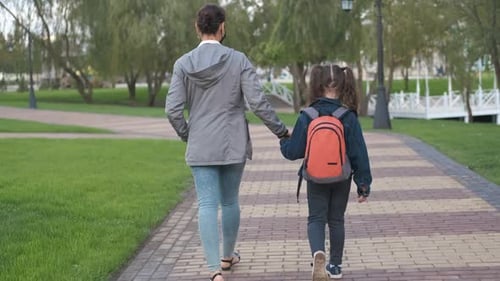 Mutter führt das Kind zur Schule.