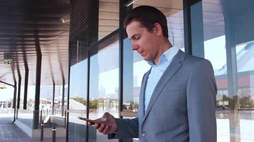Elegant businessman using smartphone in airport. Young mail entrepreneur.
