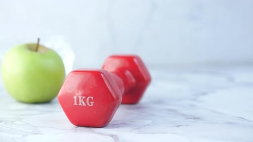 Red Dumbbells and Green Apple Representing a Healthy Lifestyle