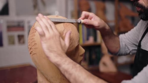 Artist Smoothing Sculpture with Rasp in Studio