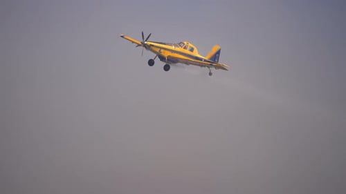 Yellow Crop Duster Airplane Sprays Field