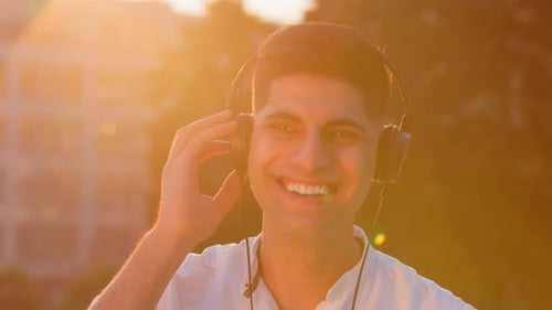 Young Man Listening to Music at Sunset
