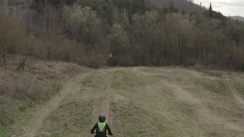 Dirt Bike Rider Leaping Over Hill in Rural Setting