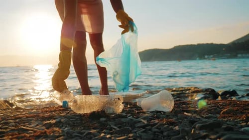 Volunteer Girl Collects Trash in the Trash Bag. Plastic Bottles and Other Trash on Sea Beach