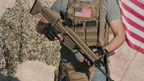 Man Holding Rifle in Front of American Flag