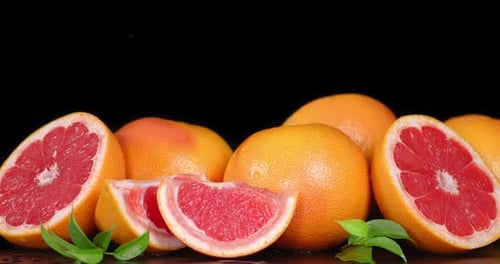 Juicy Grapefruits with Water Droplets on a Black Surface