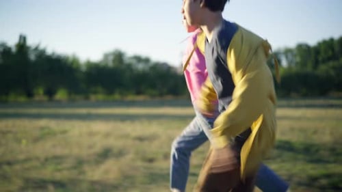 Positive Carefree Caucasian Boyfriend and Girlfriend Running on Sunny Meadow Holding Hands