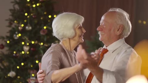 Senior Couple Dancing in Front of Christmas Tree