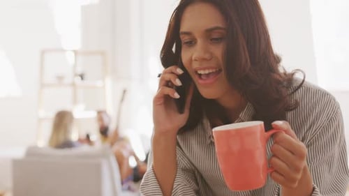 Young Woman Laughing on Phone Holding Coffee Mug