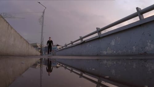 Sportive Man Running through Puddle on Urban Sidewalk