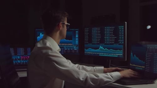 Trader working in office at night using workstation and analysis technology.