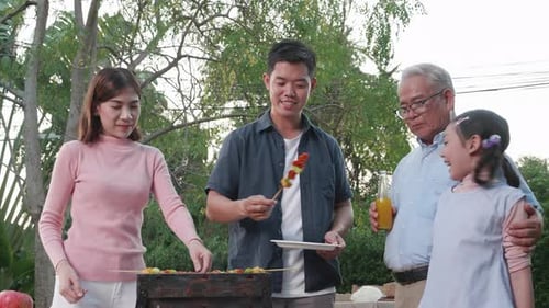 Happy Asian family having a barbecue-BBQ party together in the garden at home.
