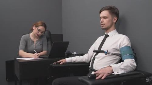 Female Polygraph Expert Examining Young Bearded Man